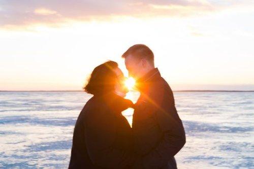 Aviopari meren rannalla aurinkon laskun aikana